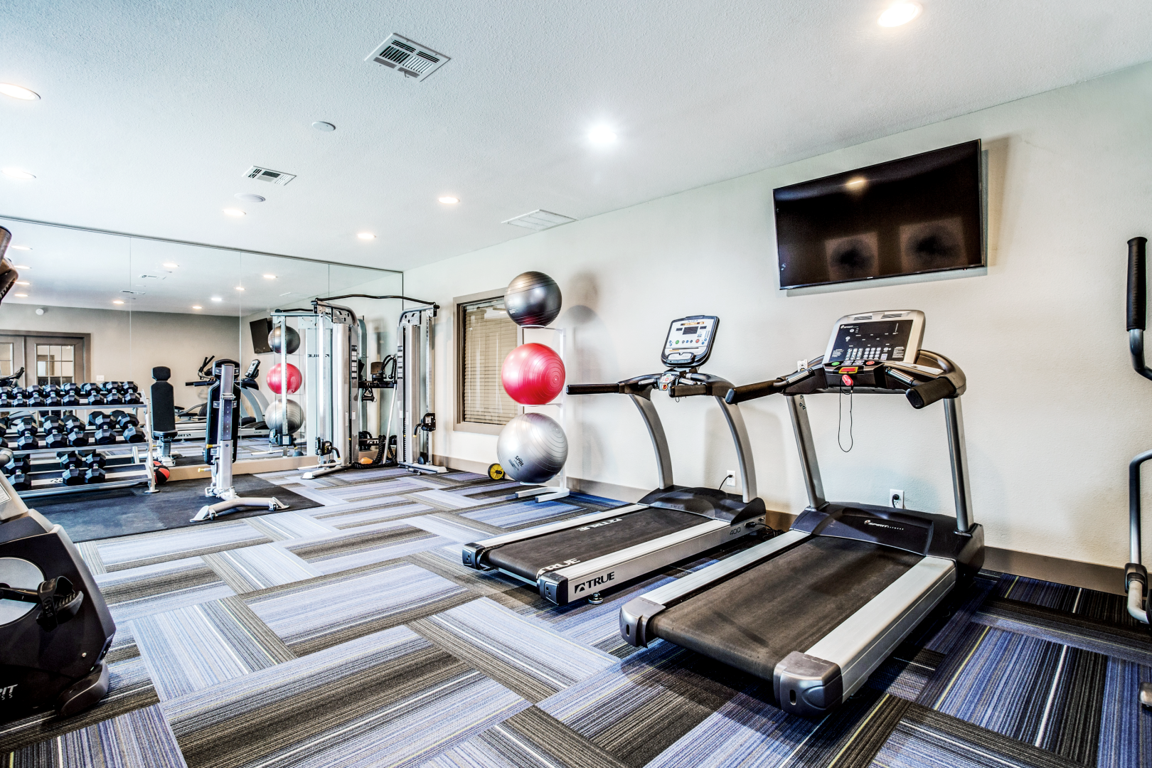 a gym room with treadmills, exercise machines and televisions at The  Mark at 2600