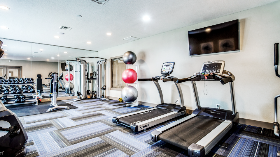 a gym room with treadmills, exercise machines and televisions at The  Mark at 2600