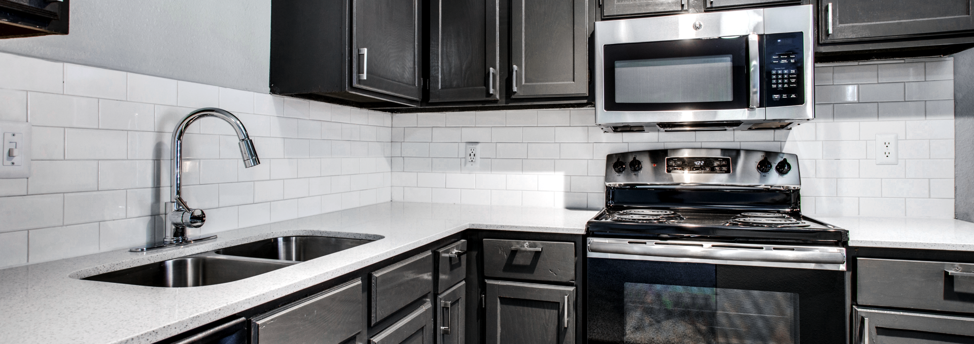 a kitchen with black cabinets and stainless steel appliances at The  Mark at 2600