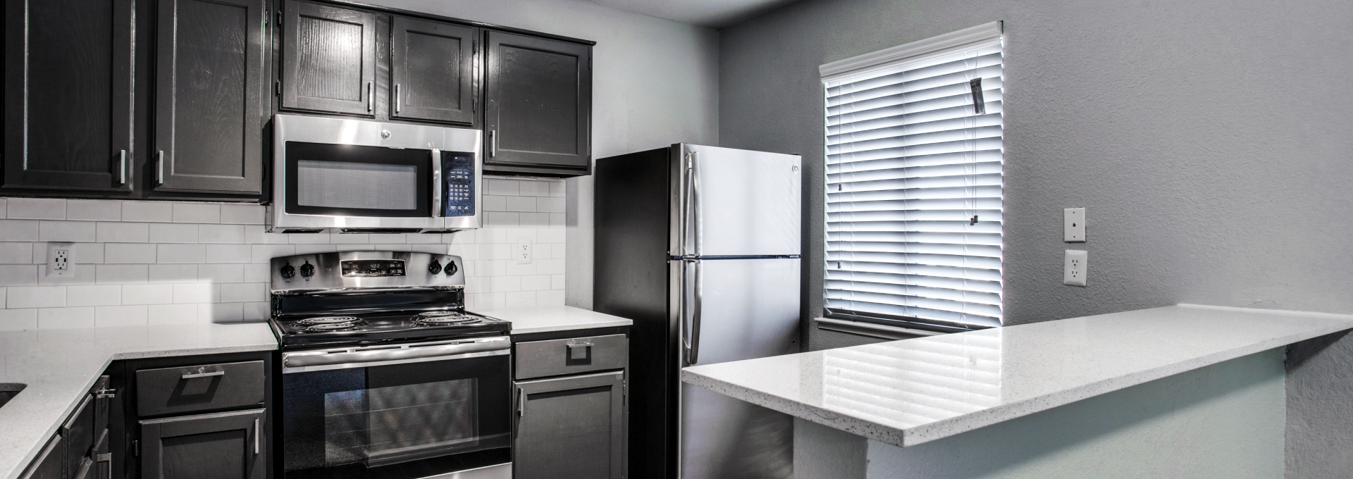 a kitchen with stainless steel appliances and black cabinets at The  Mark at 2600